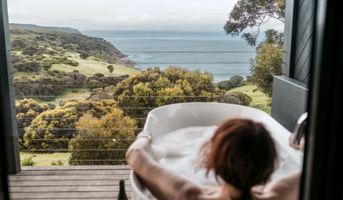 A woman taking a bath outside overlooking the beach